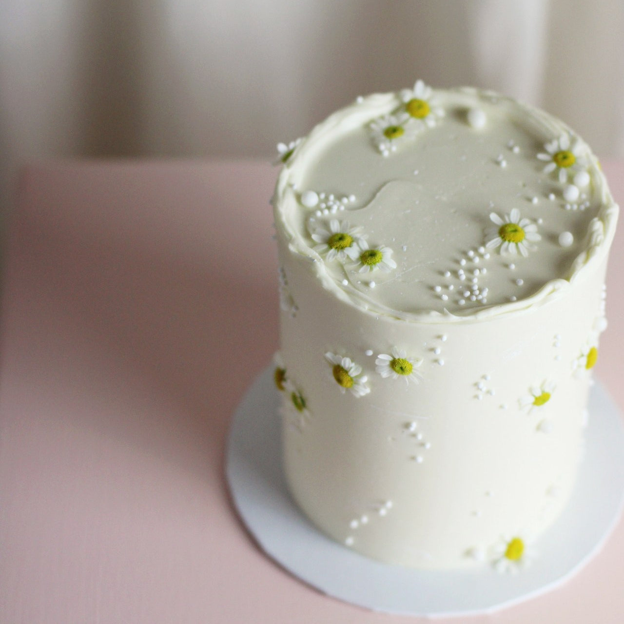 All-white gender reveal cake topped with fresh daisies