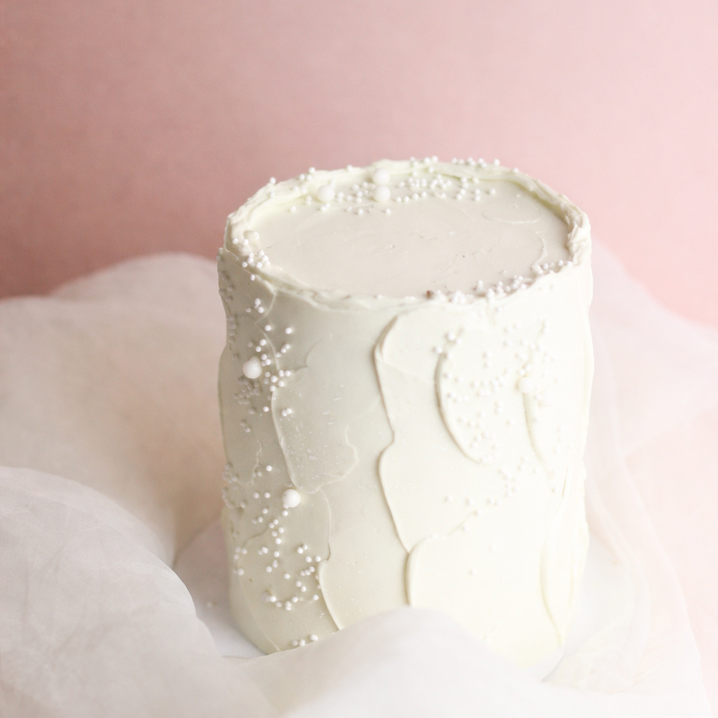 All-white cloud cake with buttercream and pearl sprinkles, perfect for a hidden-gender reveal surprise.