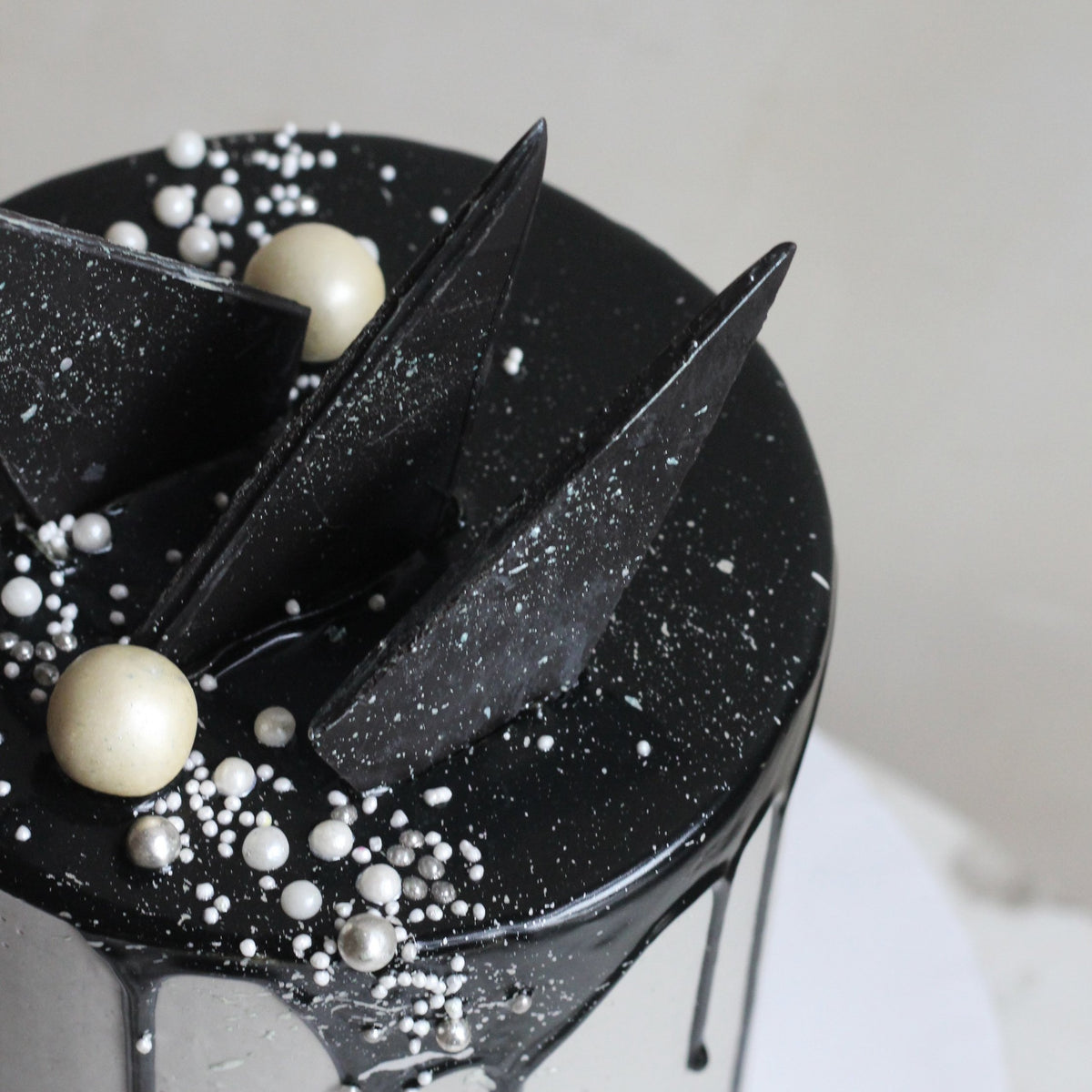The Concrete Cake - dipped in black drip icing, with geometric chocolate forms.