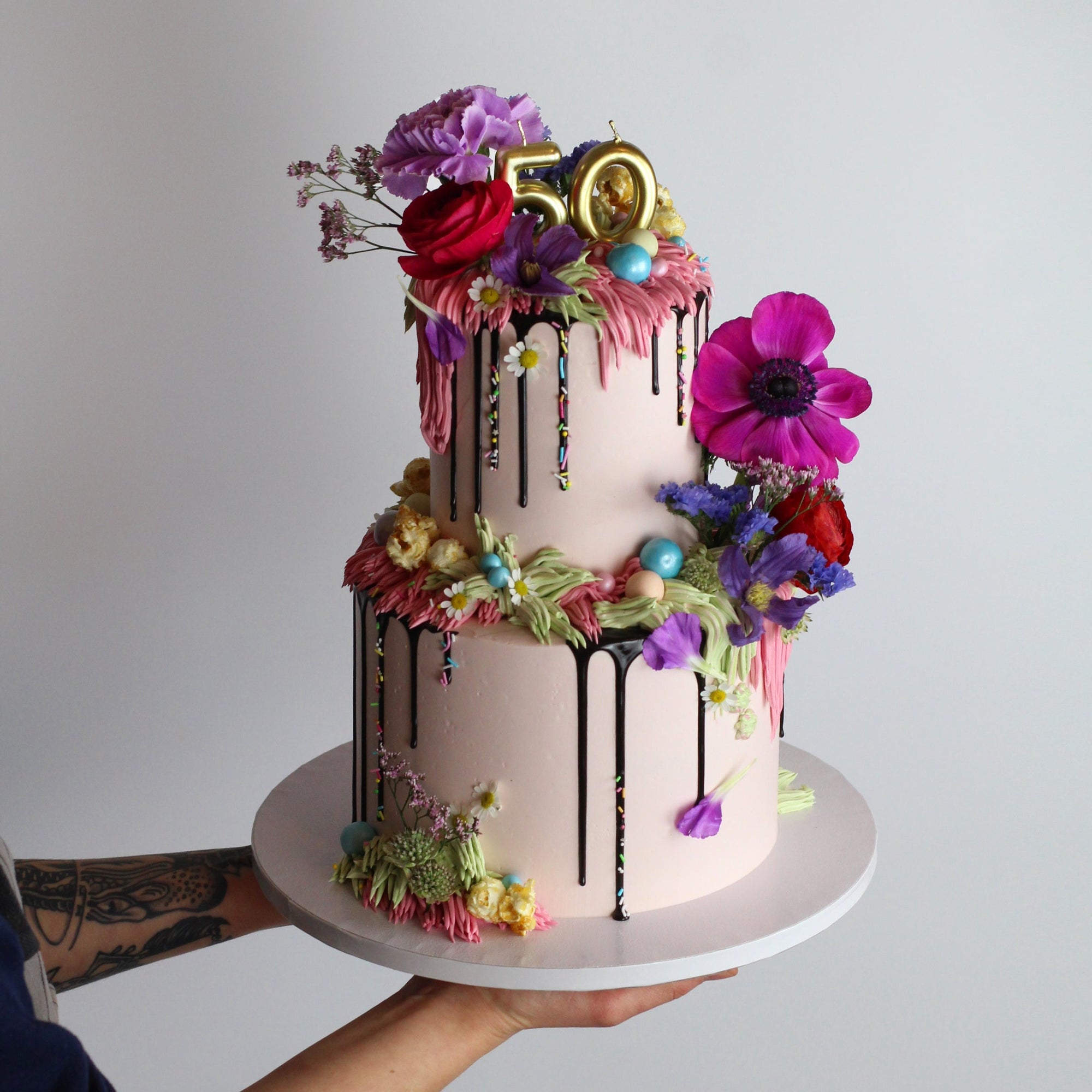 Two-tier Over The Top Cake with flowers, shaggy buttercream icing, sprinkles, candy pearls and popcorn!