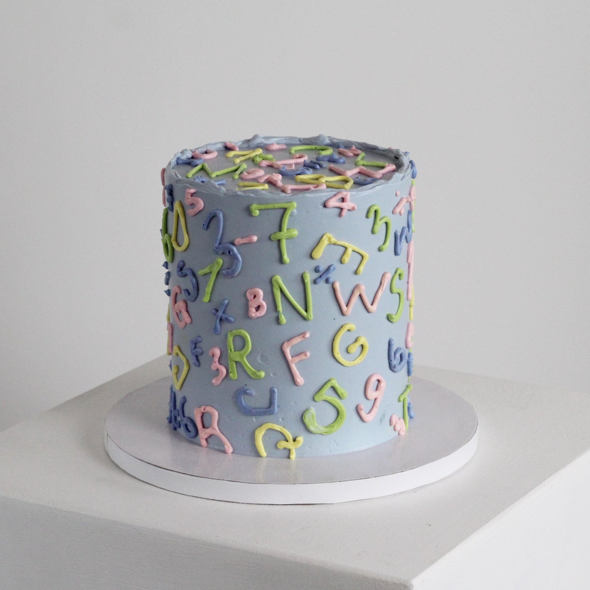 Celebrate the first day of school with this retro 90s-style ABC 123 cake, inspired by the classic Einschulung torte. Featuring hand-drawn letters and numbers in vibrant pop colors against a pastel background, it's the ultimate treat for unforgettable Einschulung enrollment parties and milestone celebrations.