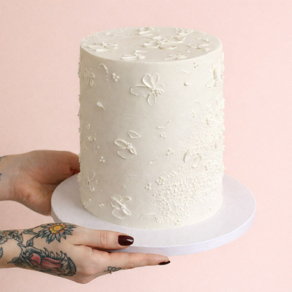 Elegant white cake decorated with delicate buttercream florals, perfect for a stylish gender reveal.