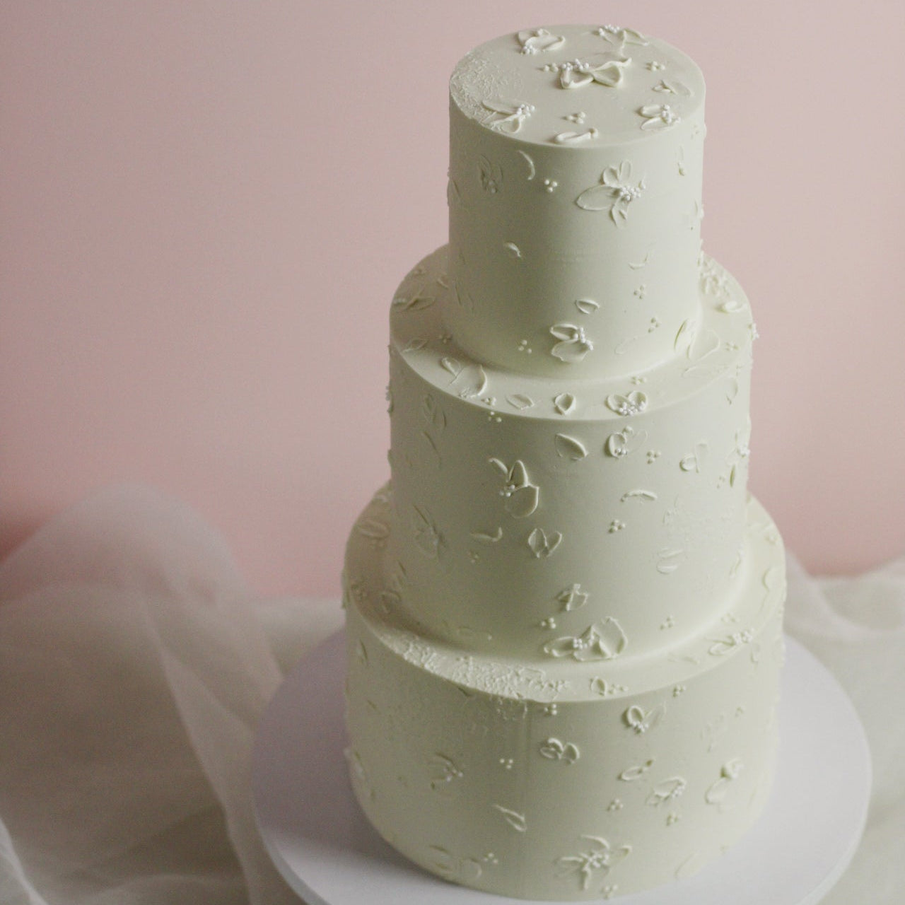 All white cake adorned with hand-painted buttercream flowers