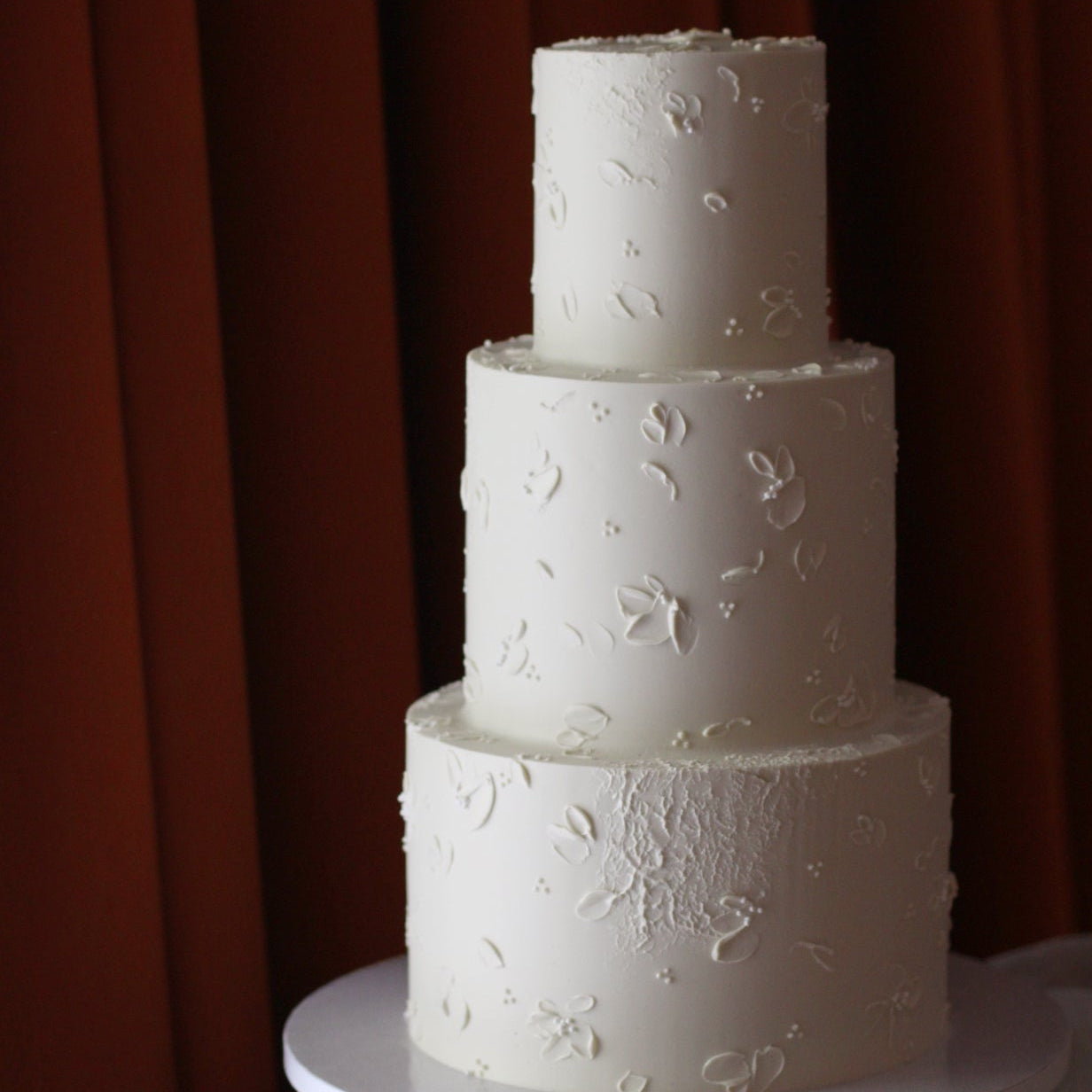 All white cake decorated with hand-painted buttercream flowers - a classic yet modern wedding cake