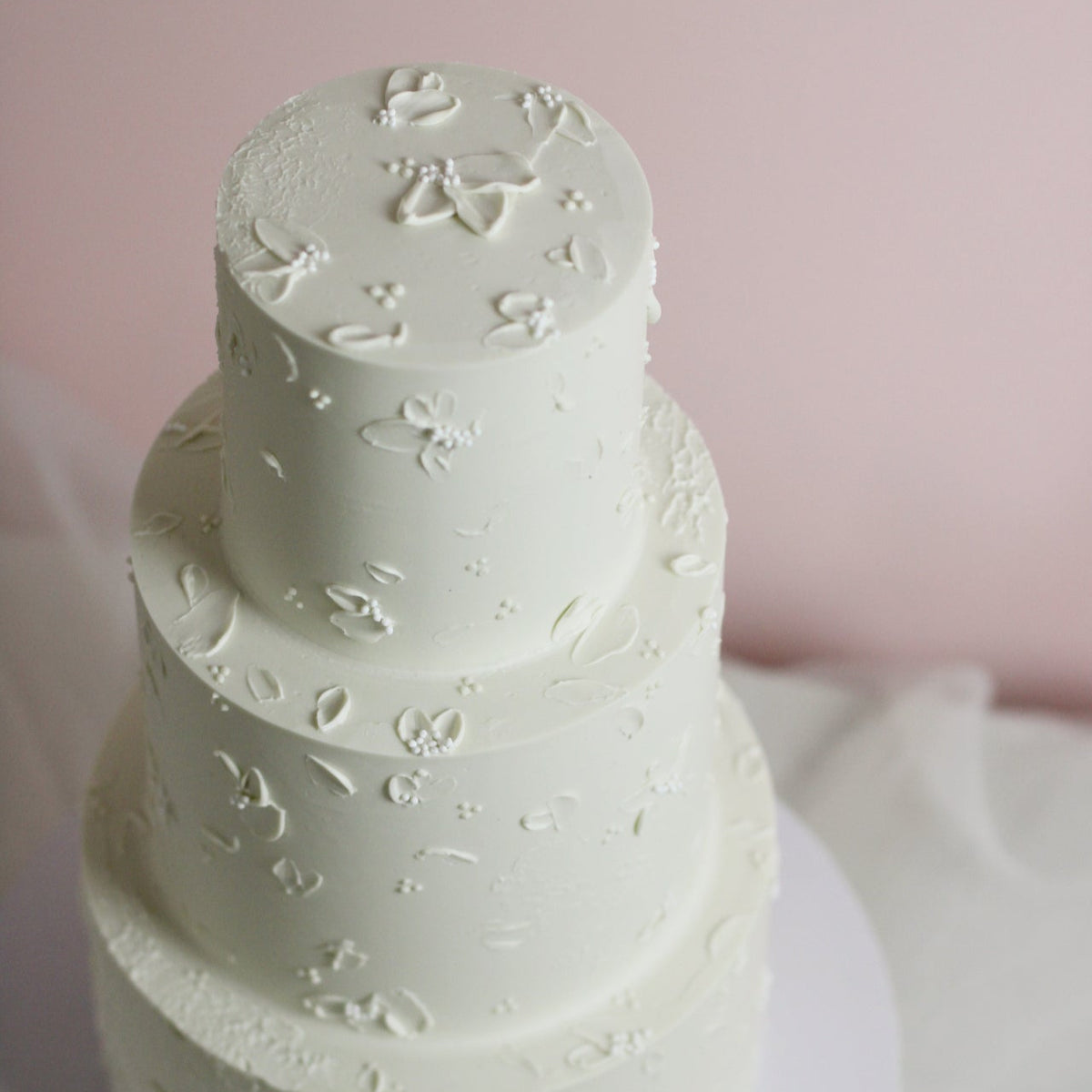 All white cake adorned with hand-painted buttercream flowers - a classic yet modern wedding cake