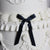 Vintage-style white buttercream cake with elegant piping and black silk bows for a timeless finish.
