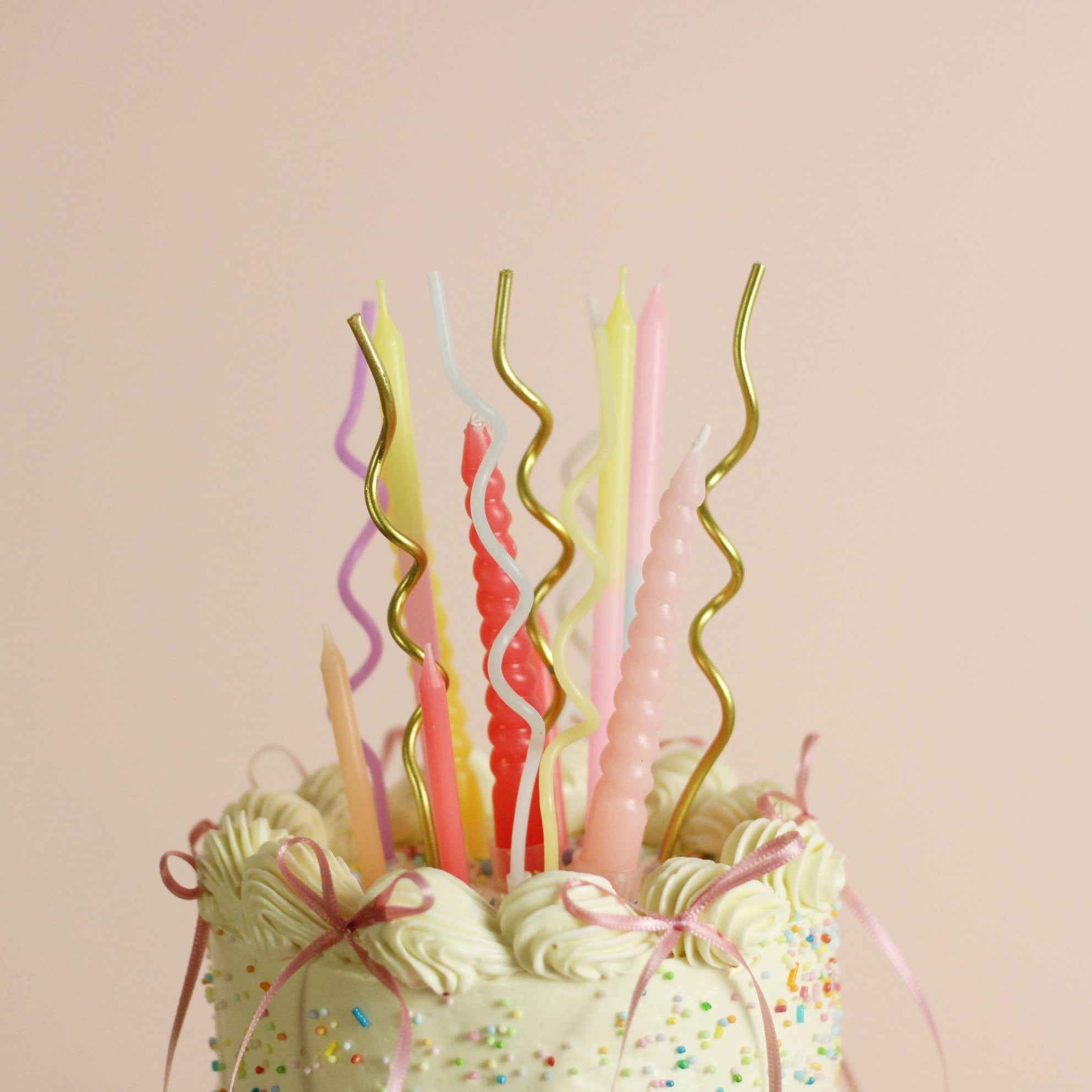 Customizable buttercream birthday cake with vintage piping, rainbow sprinkles, and ribbon bow details. Choose your preferred cake color and frill color, with an optional pastel candle add-on for an extra festive touch. Perfect for birthdays, celebrations, and special occasions in Berlin.