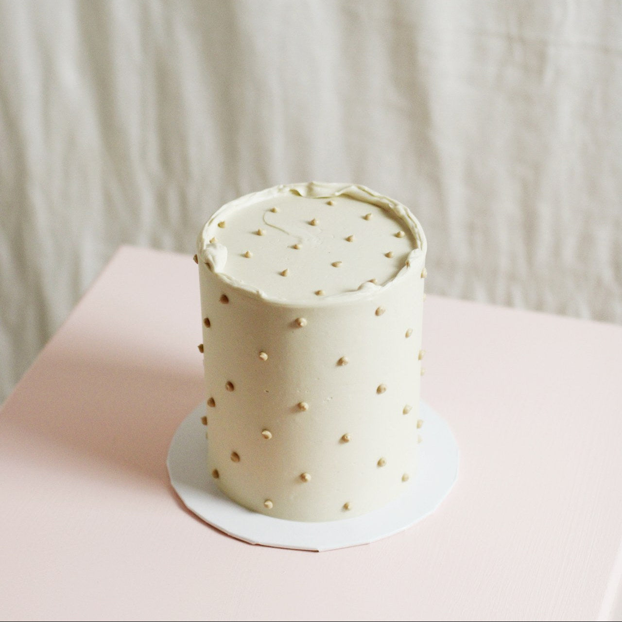 All-white gender reveal cake with tiny buttercream dots.