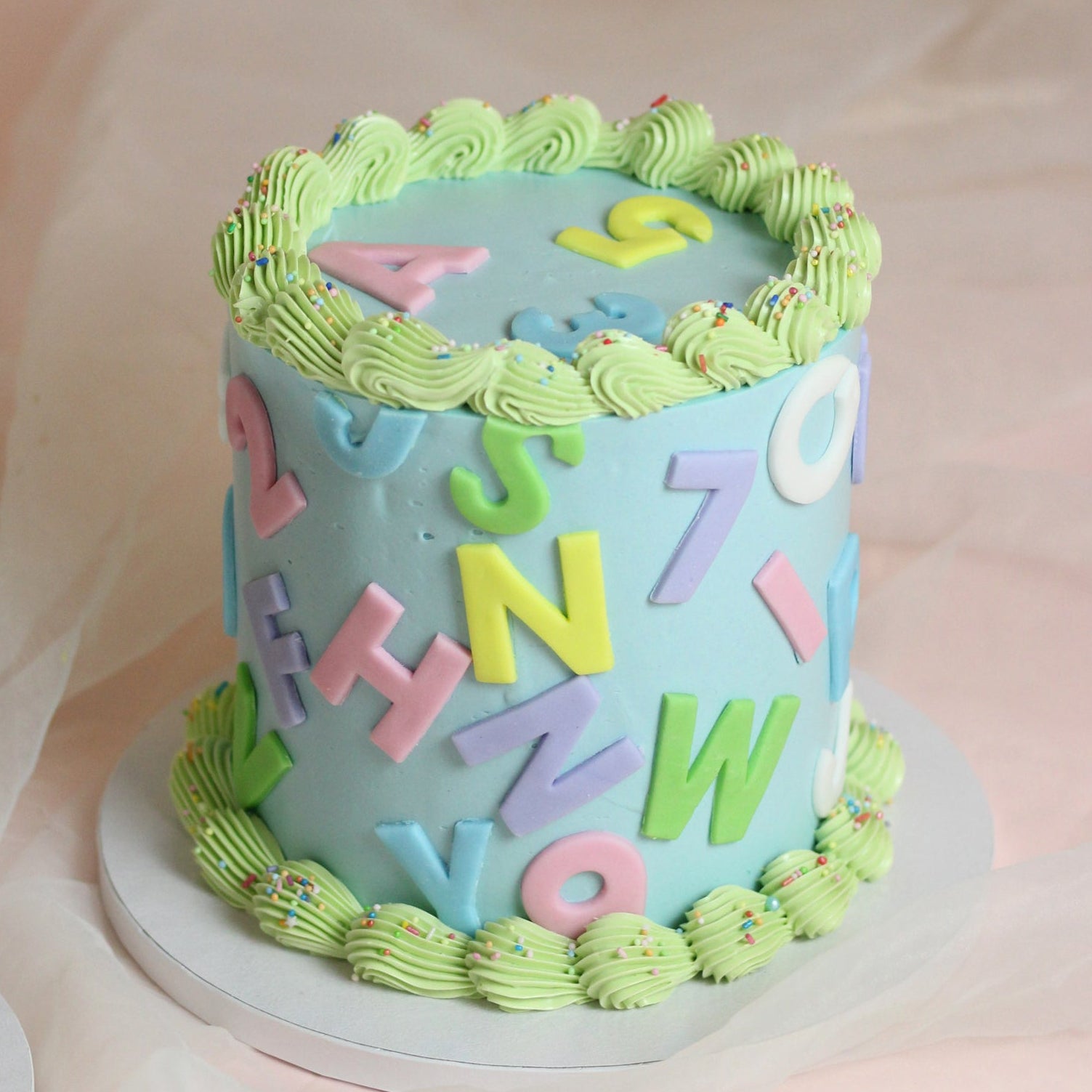 Celebrate the first day of school with our custom Einschulung Party cake. Features a smooth pastel buttercream base with colorful fondant letters, vintage piping, and a default dusting of sprinkles. The perfect centerpiece for a school enrollment party!