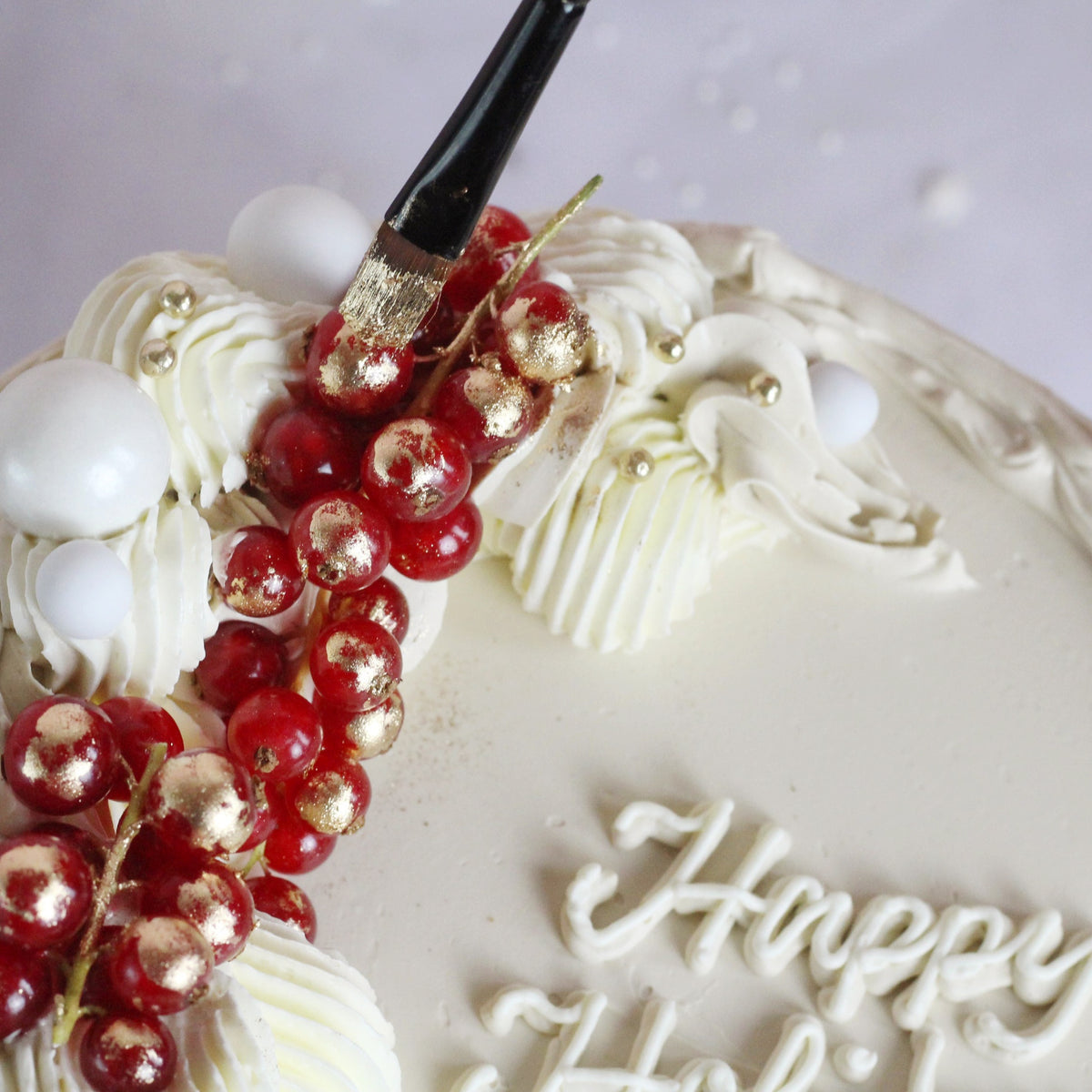 Festive All-white cake decorated with fresh cranberries and gold hand-painted gold details, perfect for elegant celebrations, festive dessert tables, and special occasions.