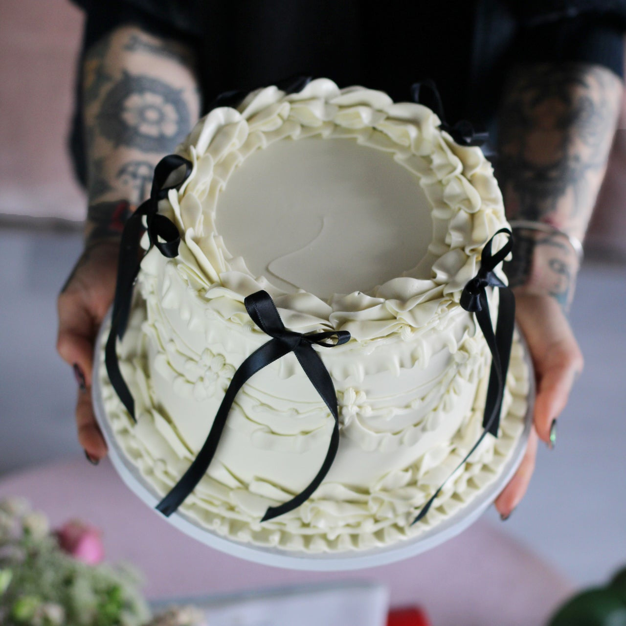 Vintage-style white buttercream cake with elegant piping and black silk bows for a timeless finish.
