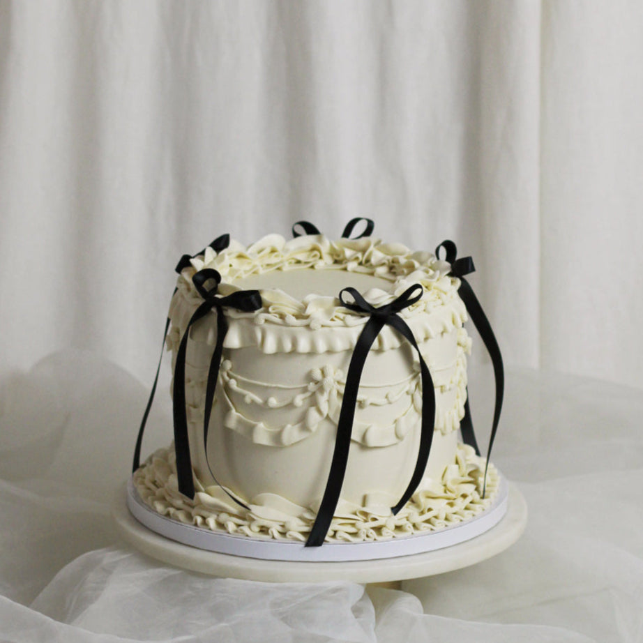 Vintage-style white buttercream cake adorned with black silk bows - add your own twist. Choose your favorite size and flavor.
Each cake is handmade at our Kreuzberg studio and delivered across Berlin.