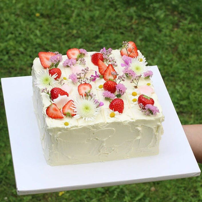 Picnic party cake with white textured buttercream. Decorated with strawberries and fresh flowers - easy to serve