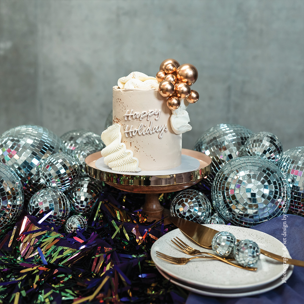 Off-white festive Christmas cake with large buttercream frills and golden balls, perfect for holiday celebrations, Christmas dessert tables, and seasonal parties. Elegant and festive holiday cake.