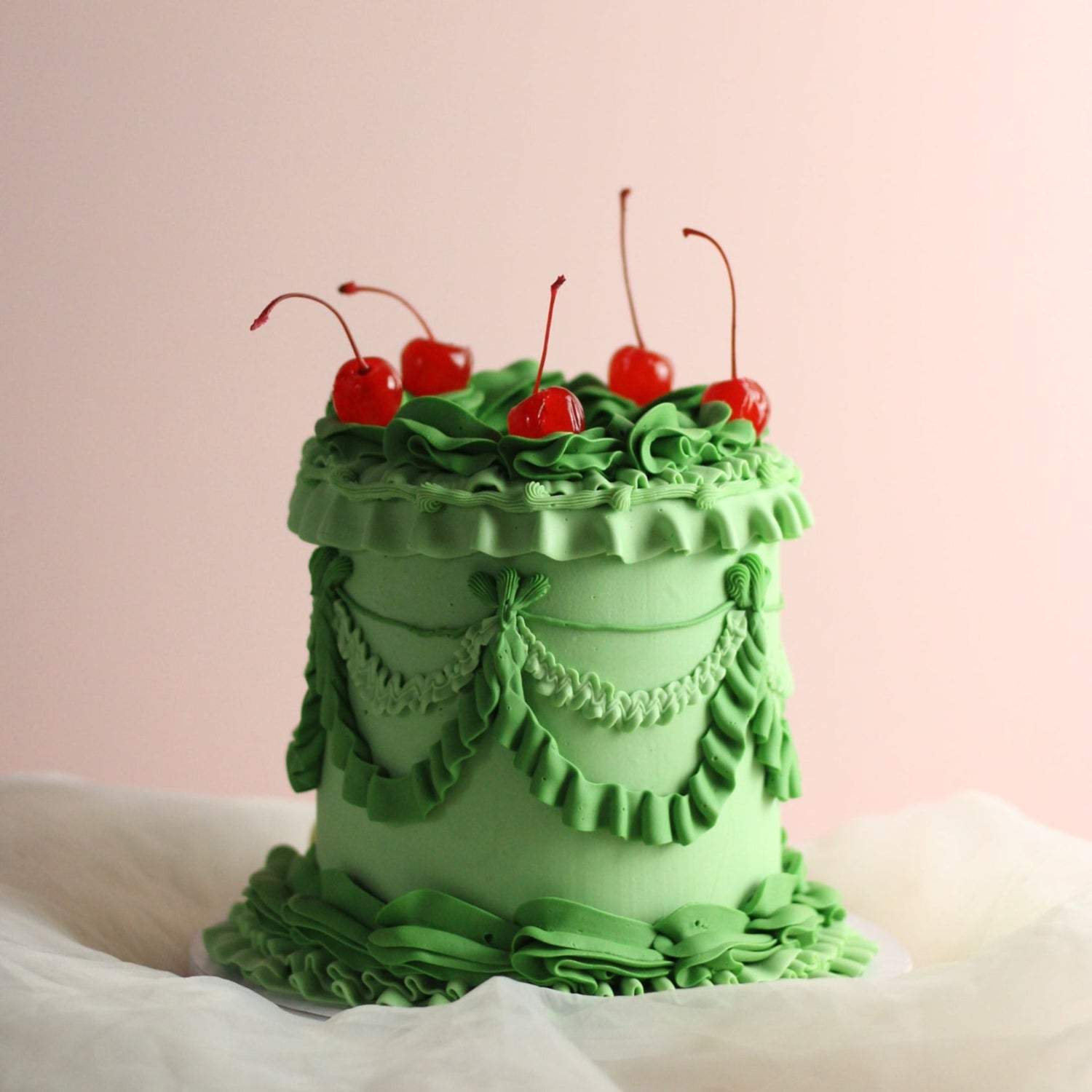 Vintage style frill cake, decorated with green frills and red cherries. Hand-made in our kreuzberg studio - delivered in Berlin