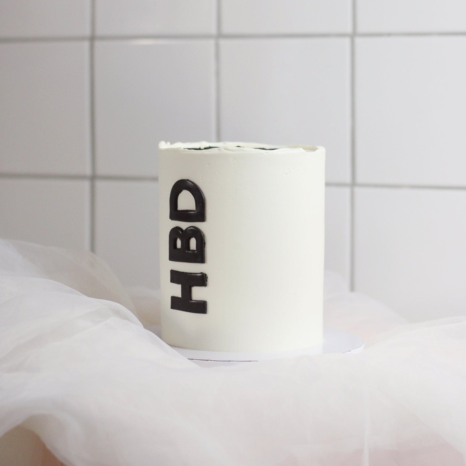 Custom-color smooth buttercream birthday cake with a simple but bold design, finished with black “HBD” fondant lettering. A modern, minimalist celebration cake.