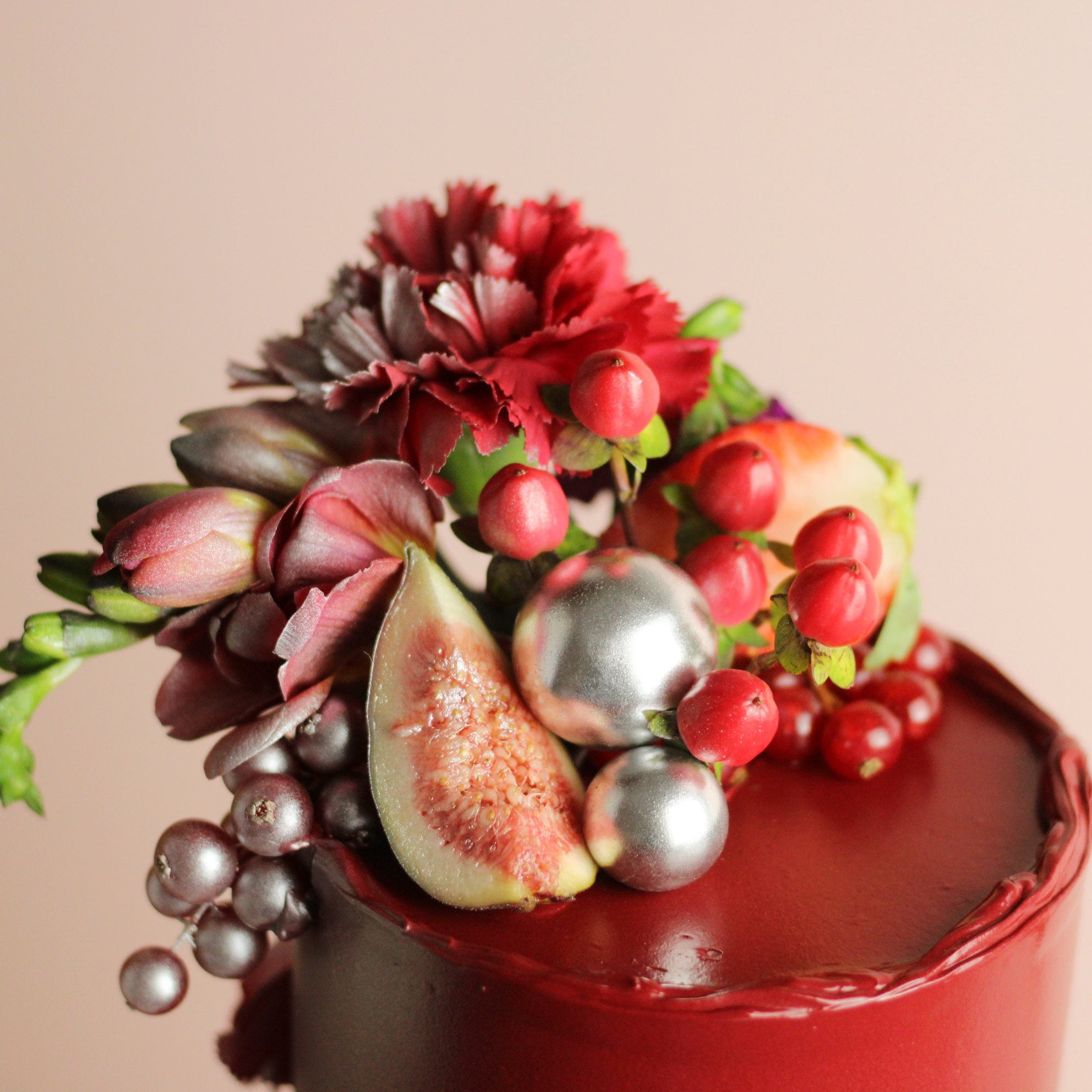 Wine-red celebration cake with figs, berries, and fresh florals. Elegant two-tier design for birthdays and special events.
