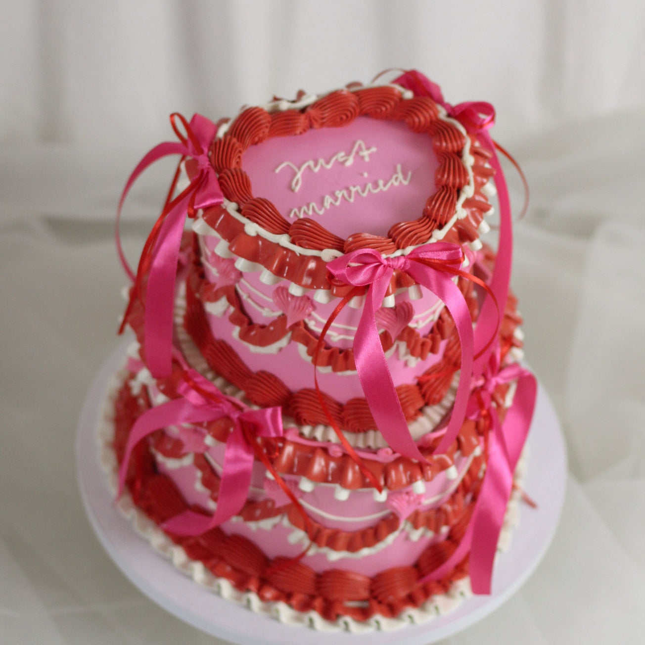 Heart shaped two tier cake with vintage style red and pink frills and hot pink silk bows. - MAde in our kreuzberg studio, delivered in Berlin