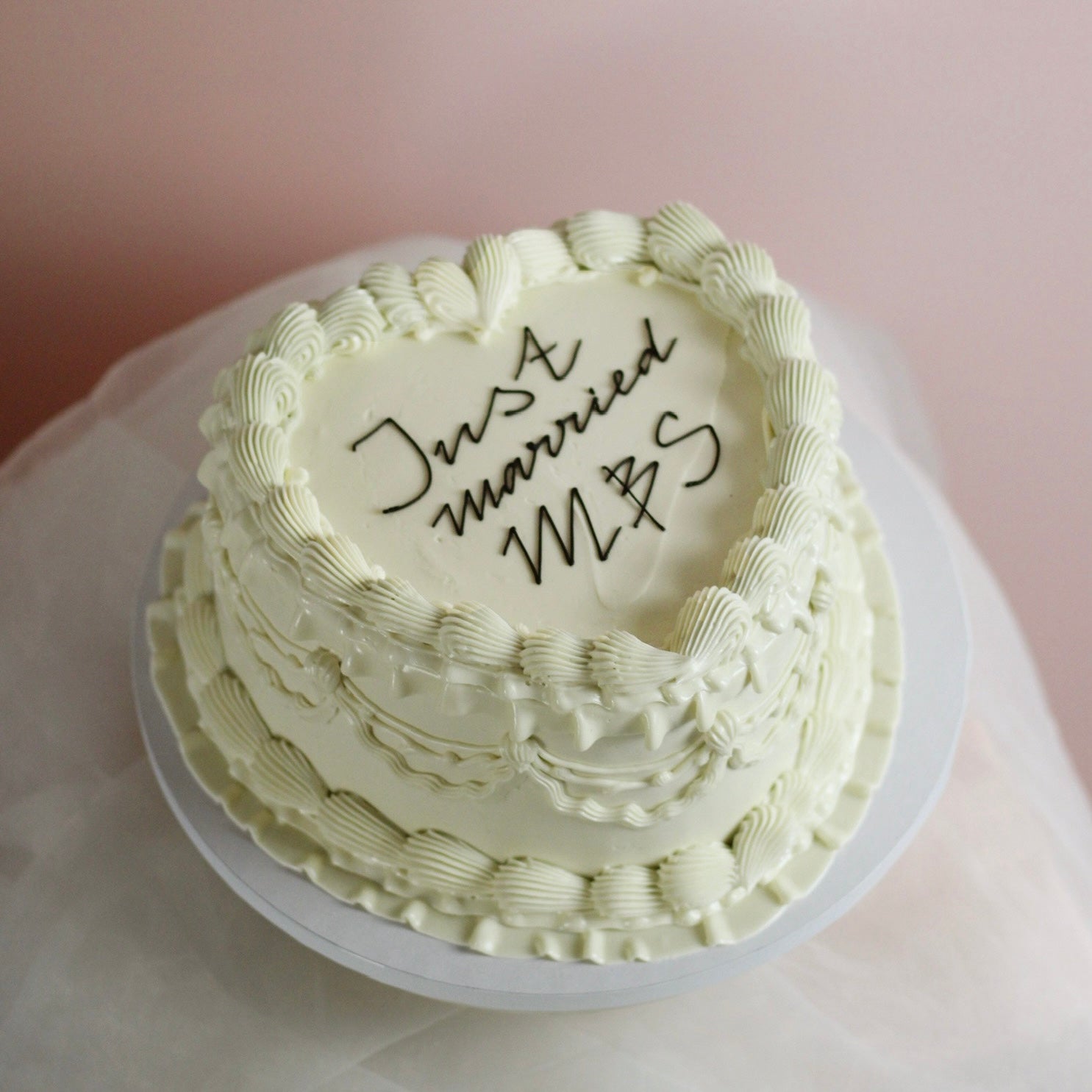 All-white heart-shaped wedding cake with message on top.