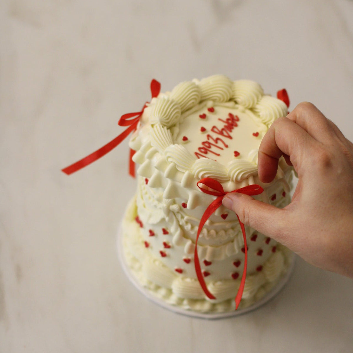 Vintage style white frill cake with little red hearts all over adorned with red silk bows.