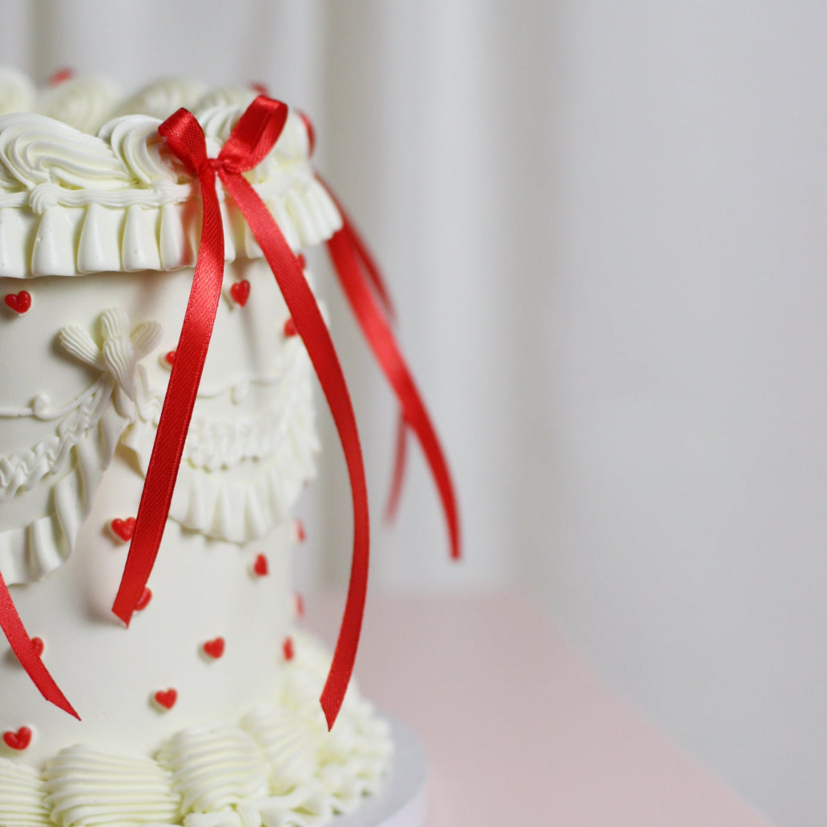 White vintage birthday cake with red hearts and red silk bows
