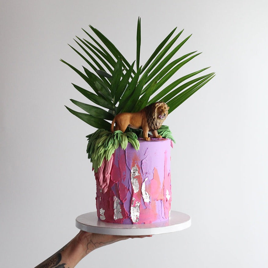 Utopia Cake - Bold colored icing and shaggy cream adorned with green leaves and a cheetah topper.