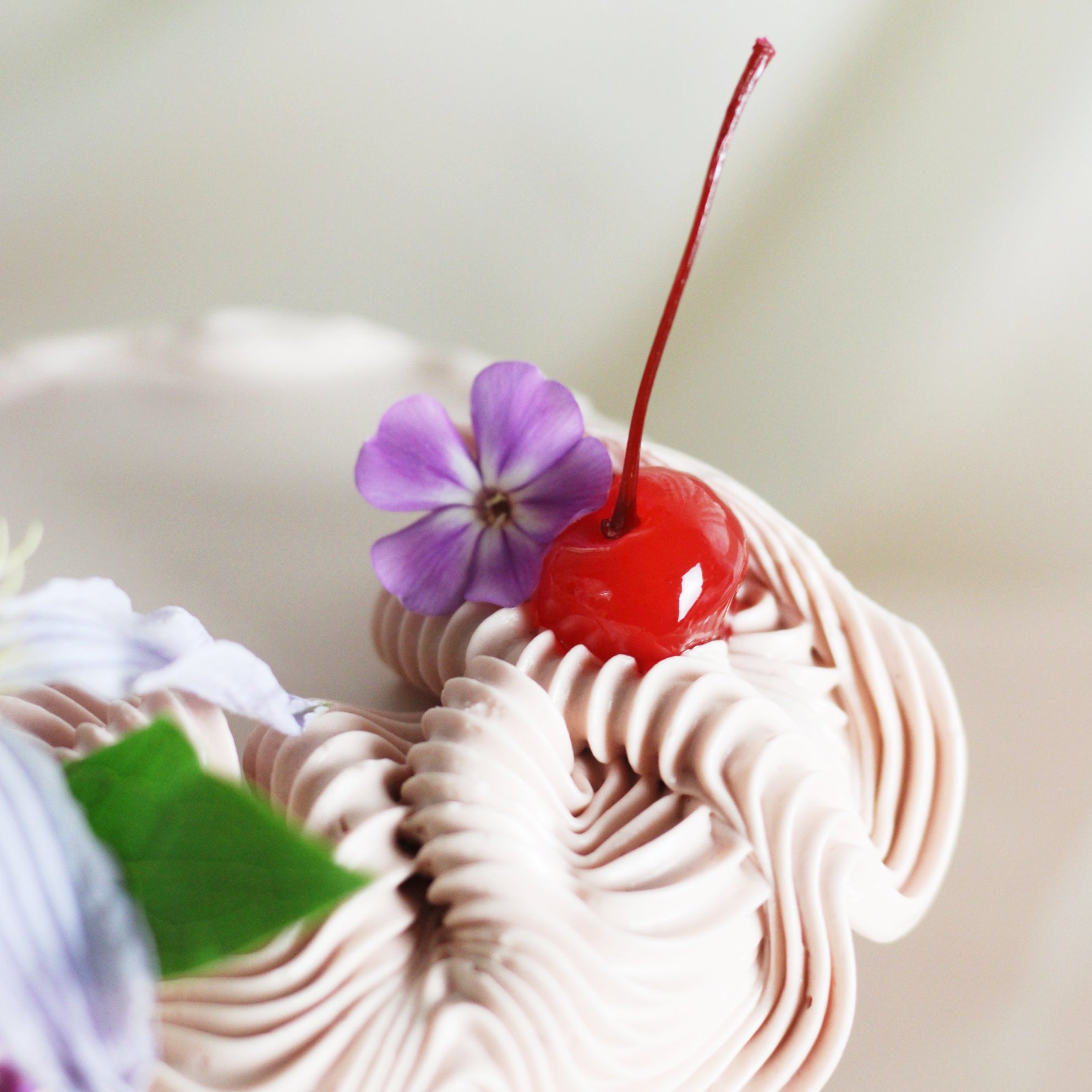 Valentine’s Day cake with light pink buttercream, maraschino cherries, and elegant decorative flowers, ideal for celebrating love.