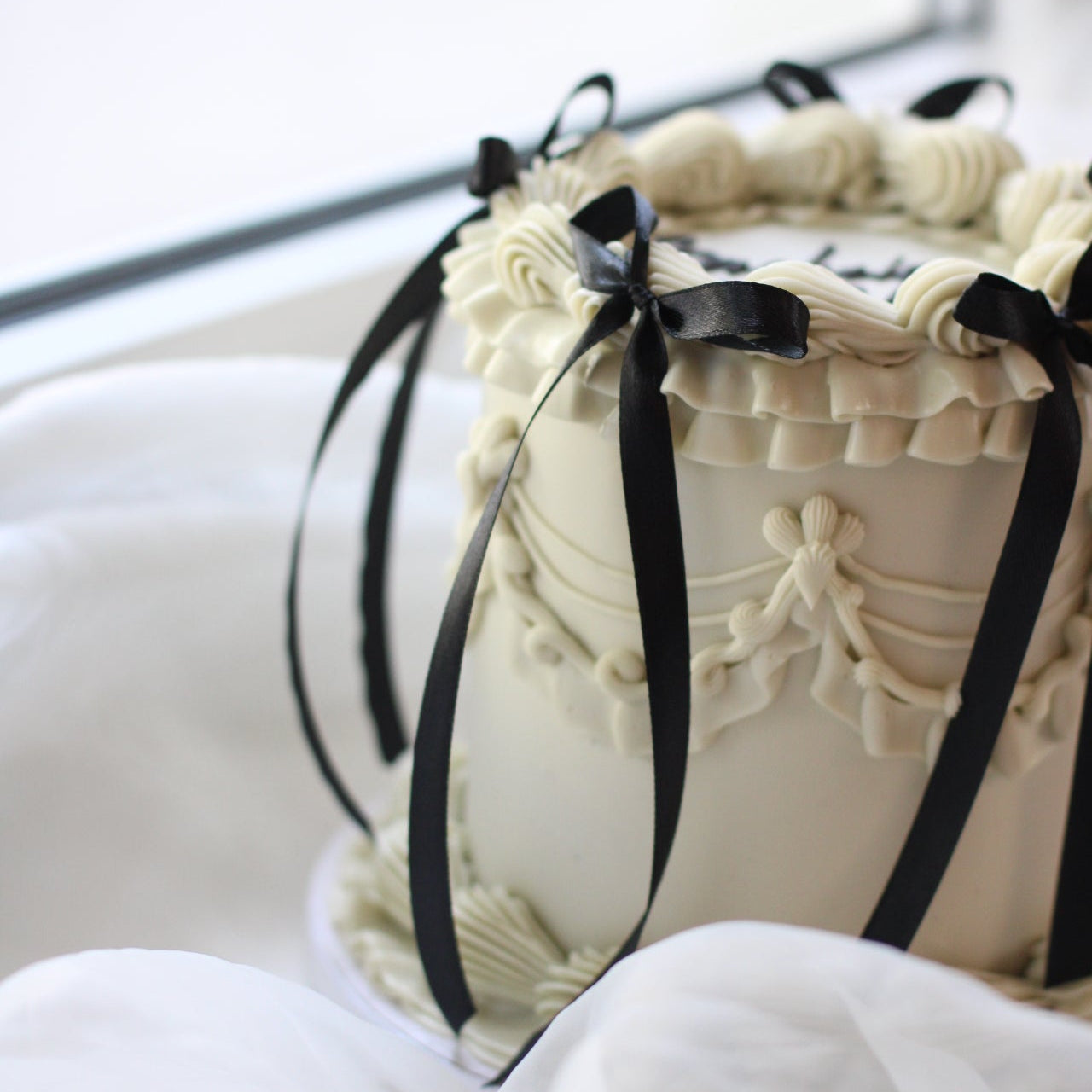 Vintage-style white buttercream cake with elegant piping and black silk bows. Birthday queen!!