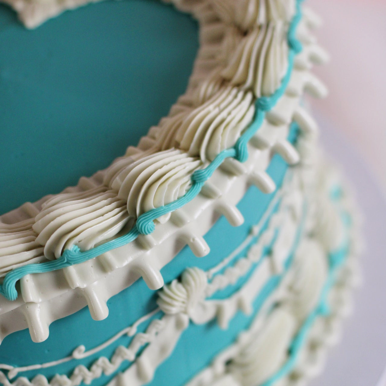 Our colorful vintage heart-shaped cake adorned with white frills on aturquise base.