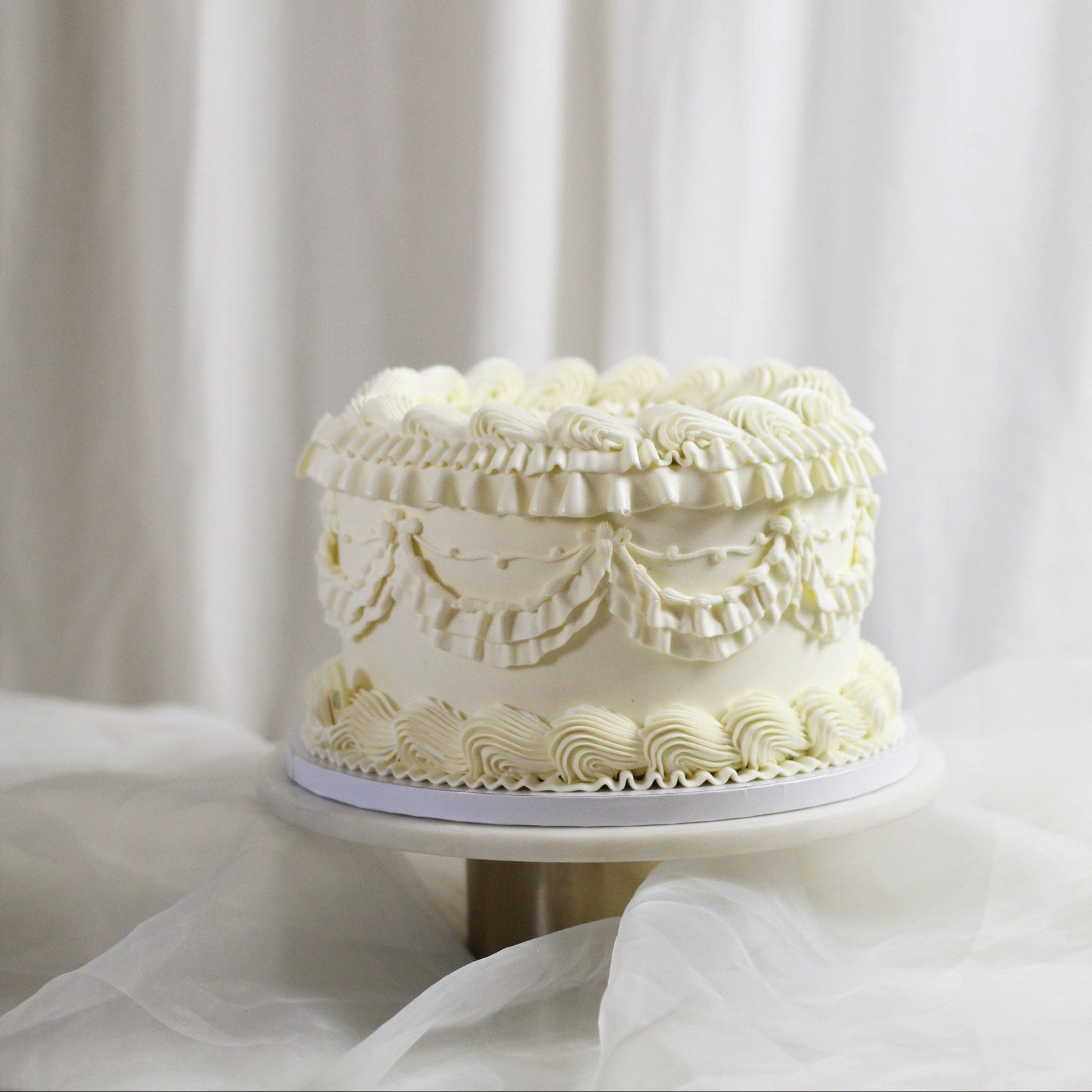 All-white gender reveal cake with vintage-style frilly buttercream for a charming, hidden surprise.