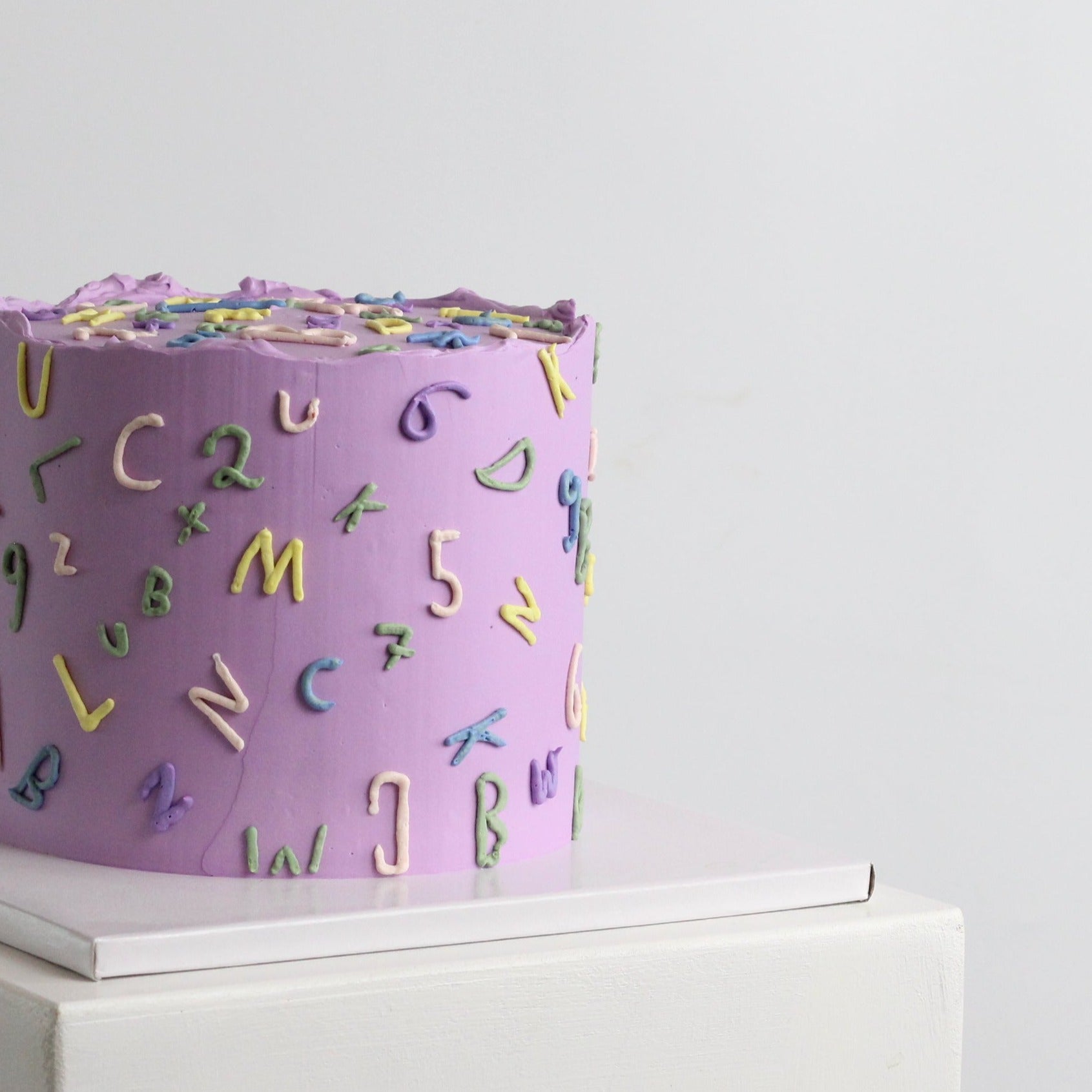 Celebrate the first day of school with this retro 90s-style ABC 123 cake, inspired by the classic Einschulung torte. Featuring hand-drawn letters and numbers in vibrant pop colors against a pastel background, it's the ultimate treat for unforgettable Einschulung enrollment parties and milestone celebrations.