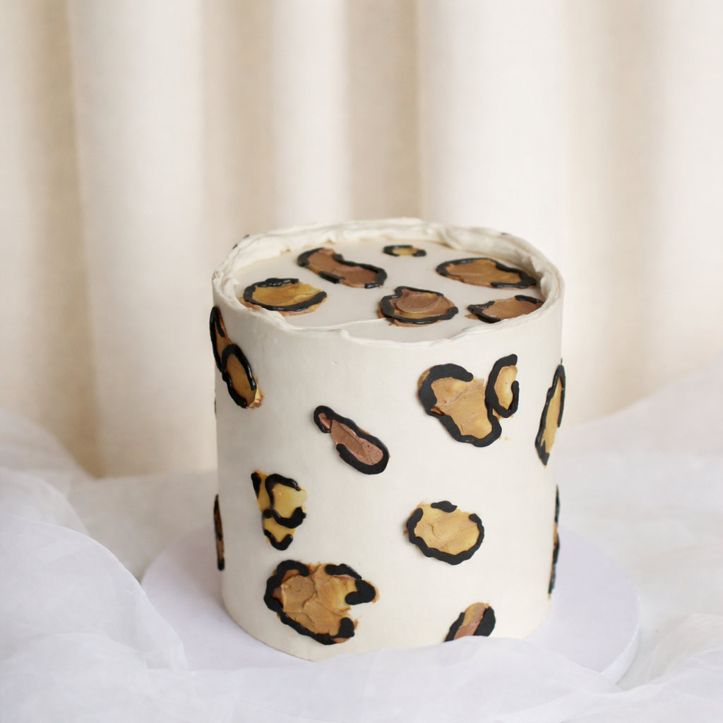 Neutral cream gender reveal cake with chic leopard buttercream