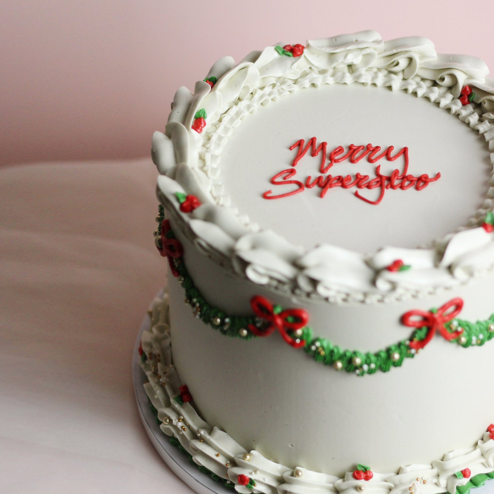 Festive white Christmas cake with red bows and green frills. Perfect for any holiday celebration.