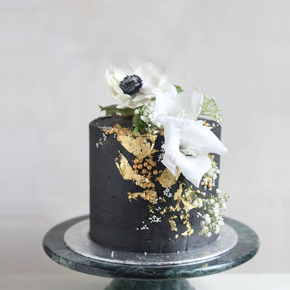 Drama Baby, Drama! Cake - Our darkest cake is sprinkled with gold details and fresh white flowers.
