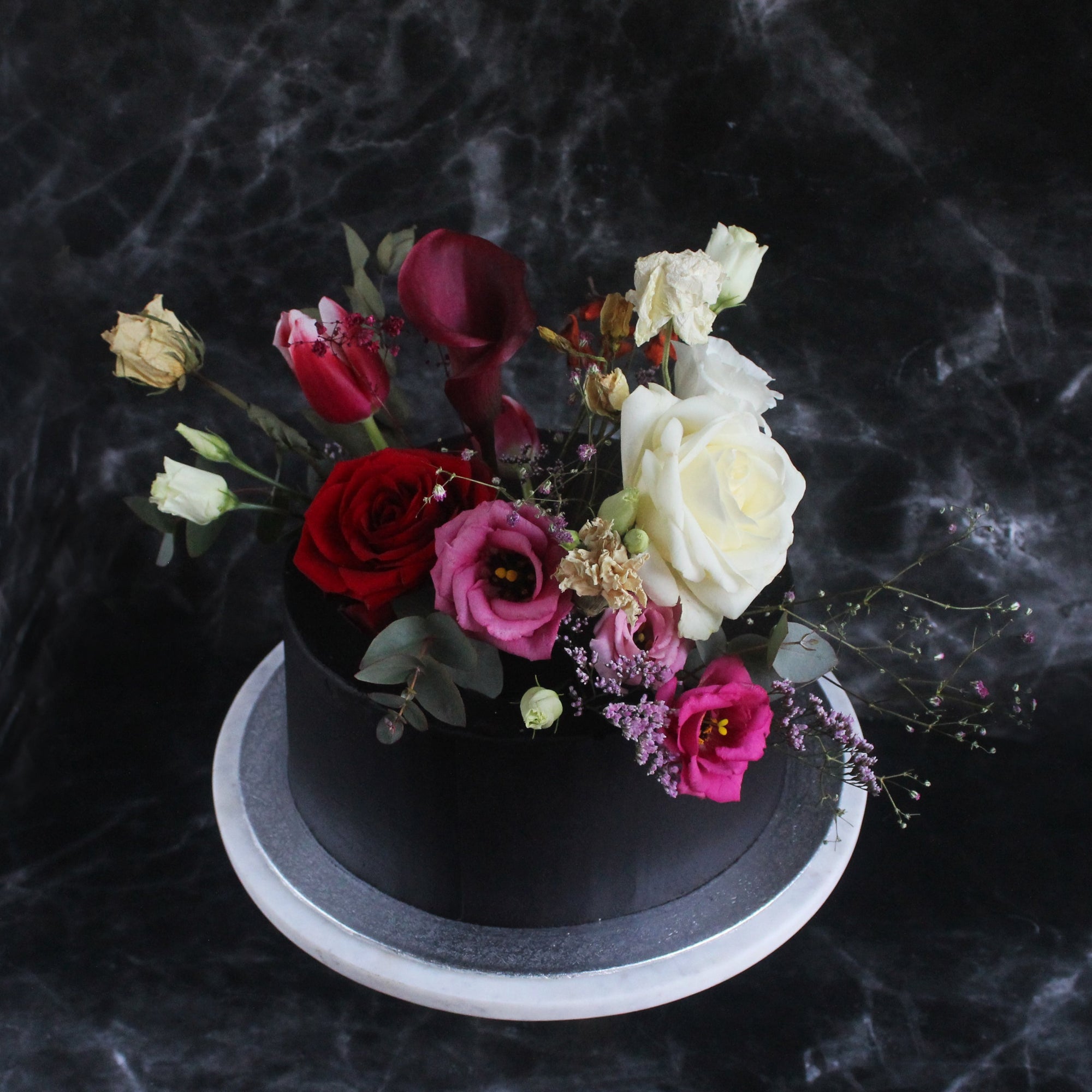 Blossom Hat Cake with black icing, metallic splashes & a funky bold headpiece of fresh flowers.