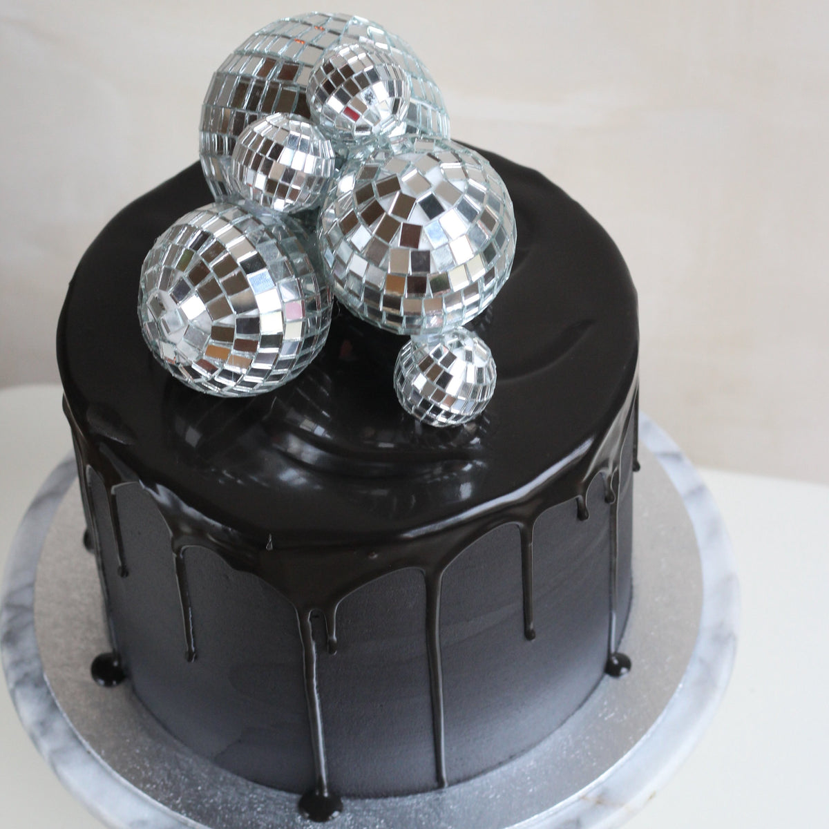Black party cake topped with shiny disco balls, perfect for birthdays, celebrations, dance parties, and glamorous dessert tables. Stylish and eye-catching cake for festive occasions.