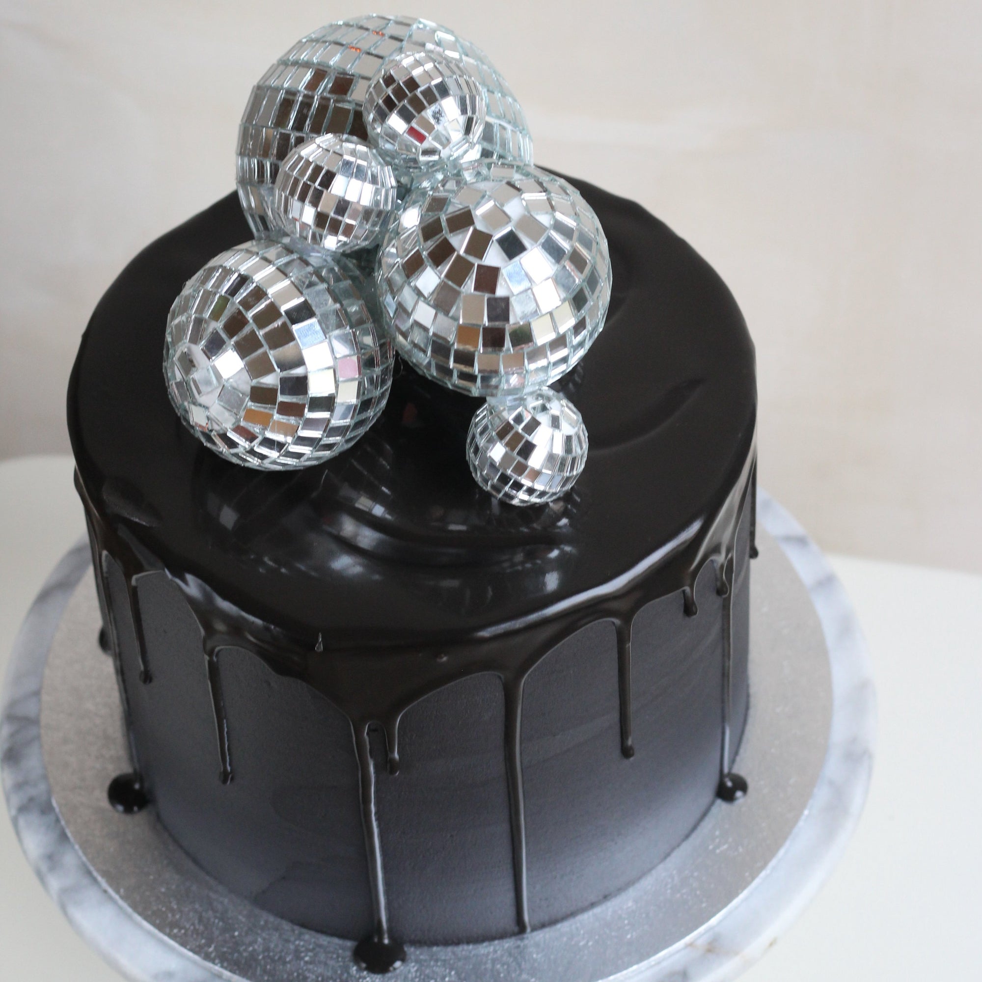 Black party cake topped with shiny disco balls, perfect for birthdays, celebrations, dance parties, and glamorous dessert tables. Stylish and eye-catching cake for festive occasions.