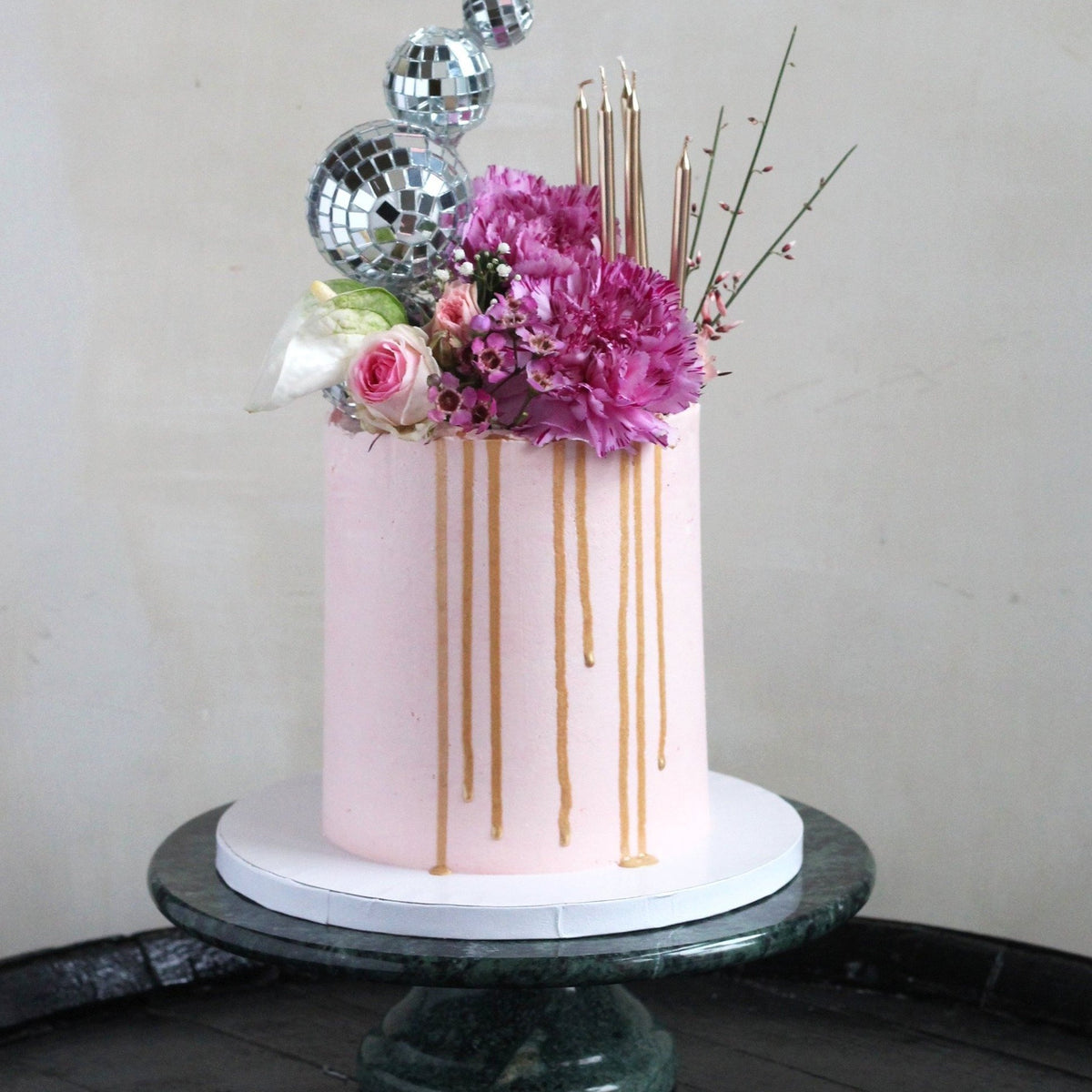 Golden Hour Cake for disco queens with pink icing, bold florals, gold drip and of course the disco balls!