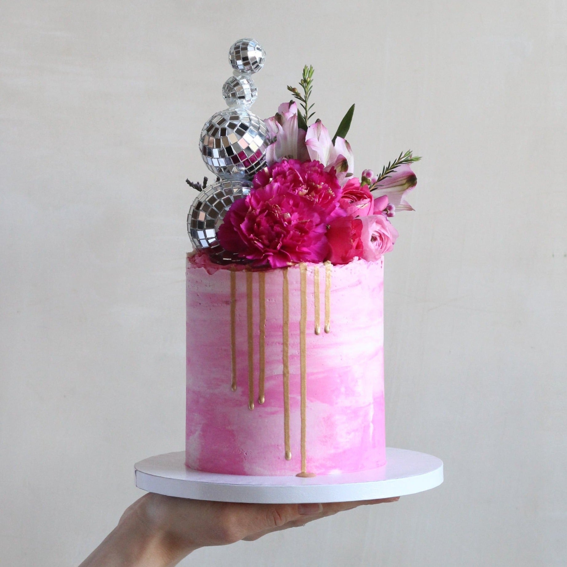 Golden Hour Cake for disco queens with pink icing, bold florals, gold drip and of course the disco balls!