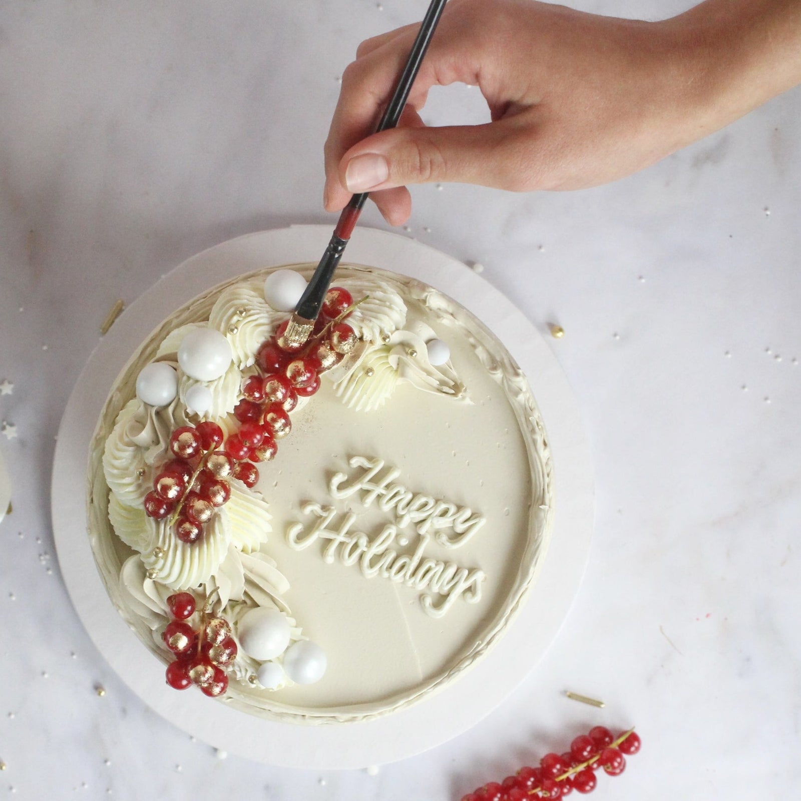 Festive All-white cake decorated with fresh cranberries and gold hand-painted gold details, perfect for elegant celebrations, festive dessert tables, and special occasions.