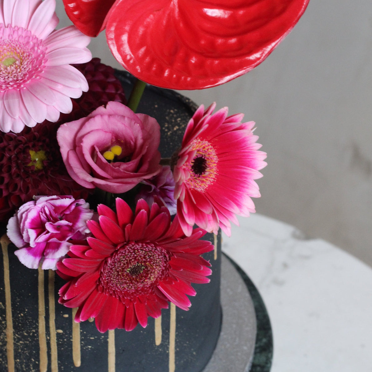 Blossom Hat Cake with black icing, metallic splashes &amp; a funky bold headpiece of fresh flowers.
