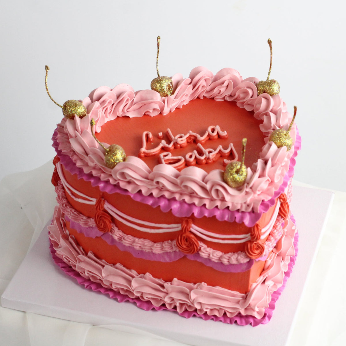Our heart-shaped cake adorned with colorful frills and golden cherries!