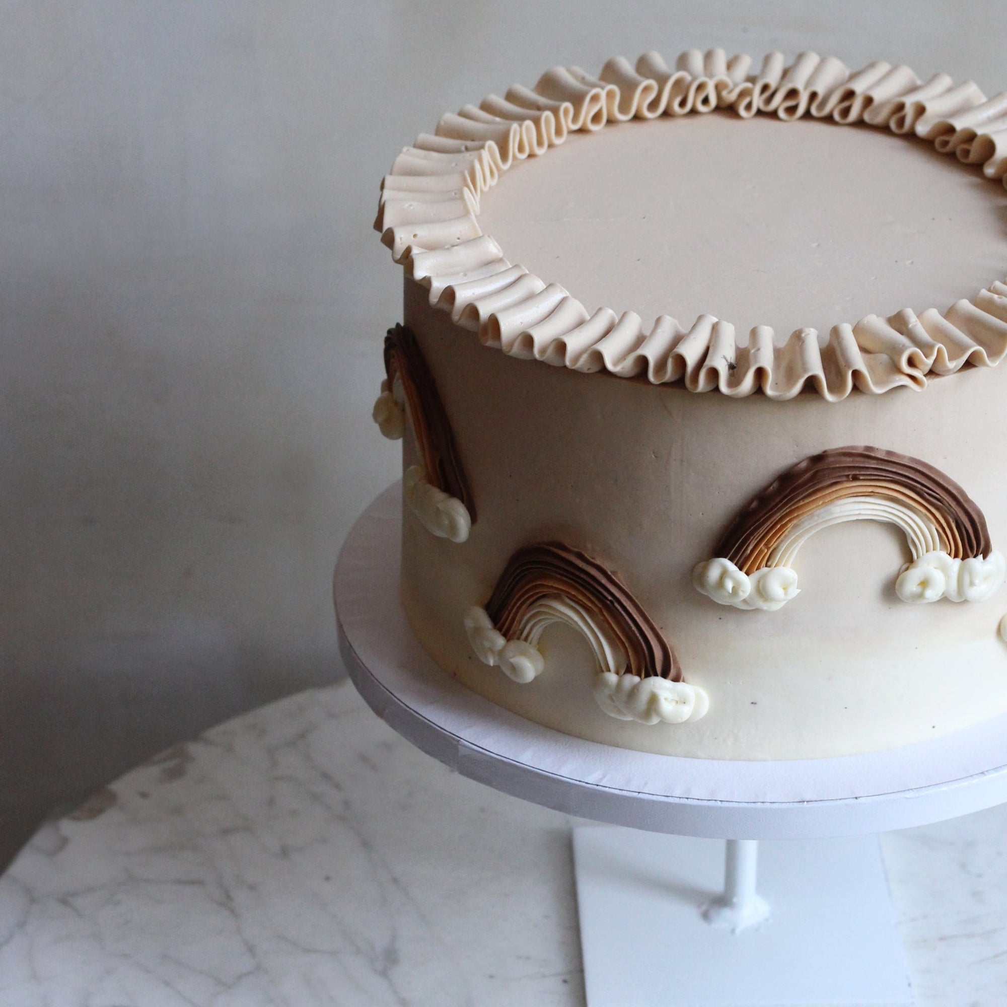 Our Rainbow Cake with custom neutral tones, 3D rainbows and creamy ruffles!