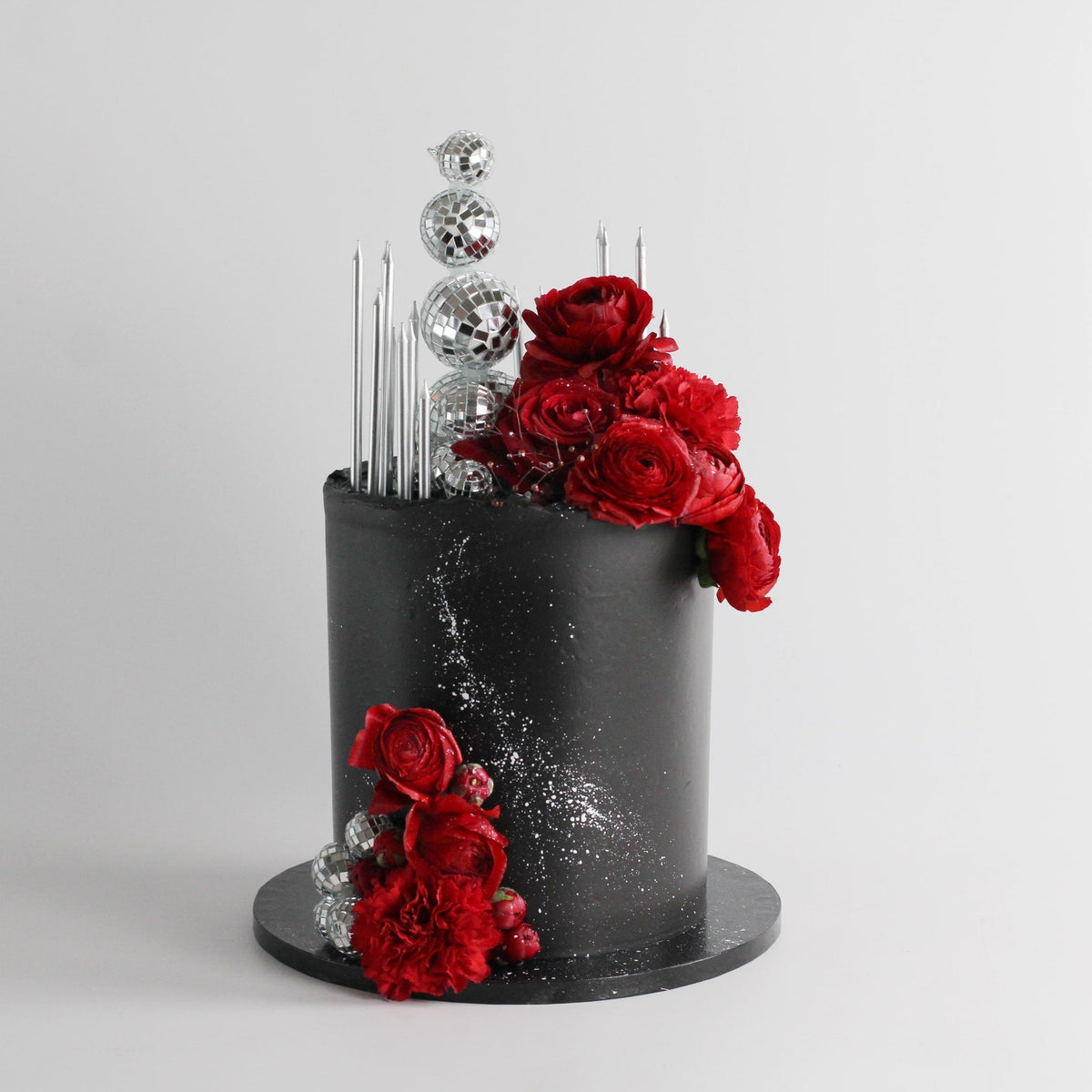 A true statement cake featuring sleek black-on-black icing, a dazzling disco ball headpiece, and bold floral details. Perfect for glamorous parties and unforgettable celebrations.