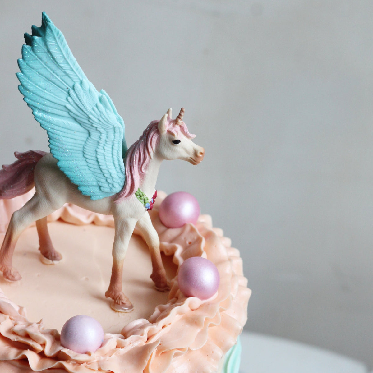 Our Rainbow Cake with peach &amp; mint ombre icing, 3D rainbows, creamy ruffles &amp; unicorn topper!