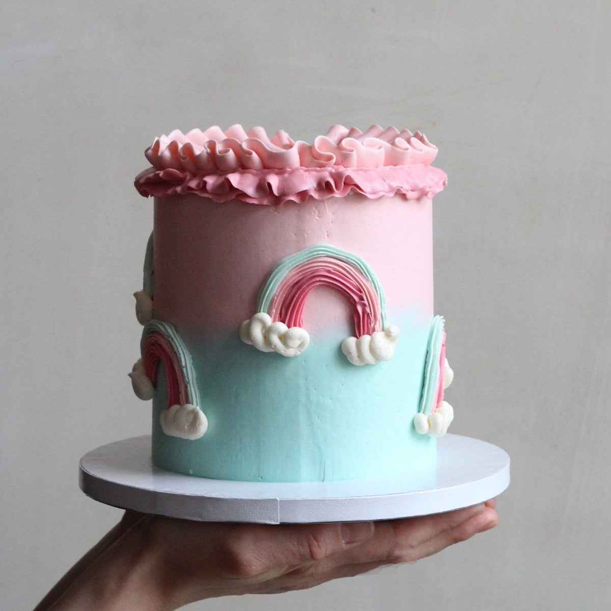 Our Rainbow Cake with pink &amp; mint icing, 3D rainbows and creamy ruffles!