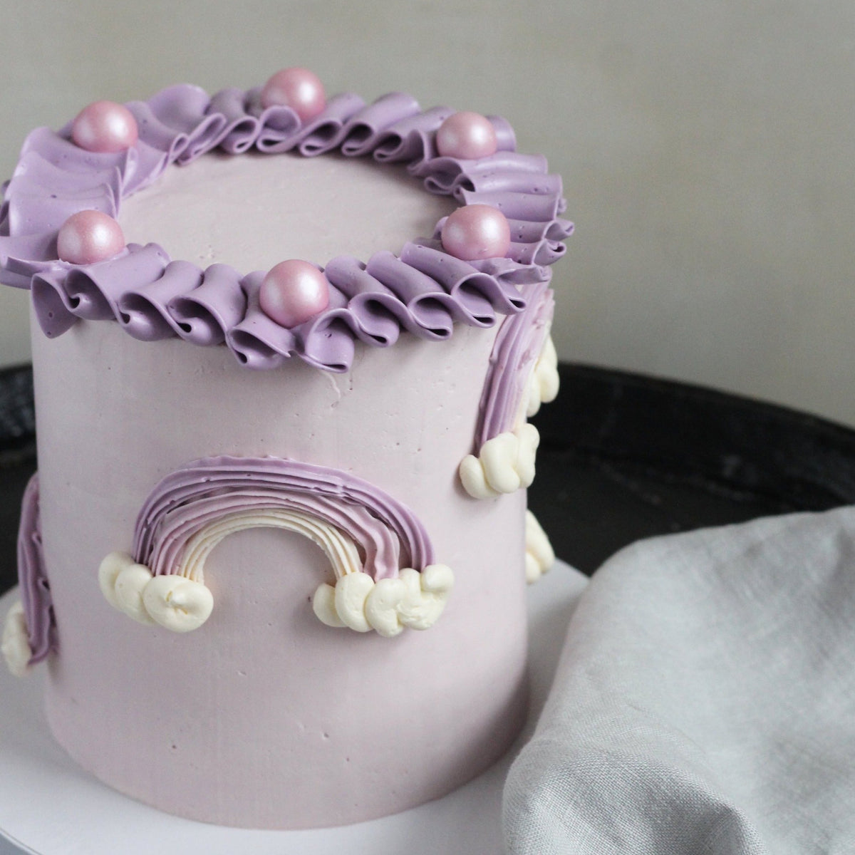 Our Rainbow Cake with custom purple tones, 3D rainbows and creamy ruffles!
