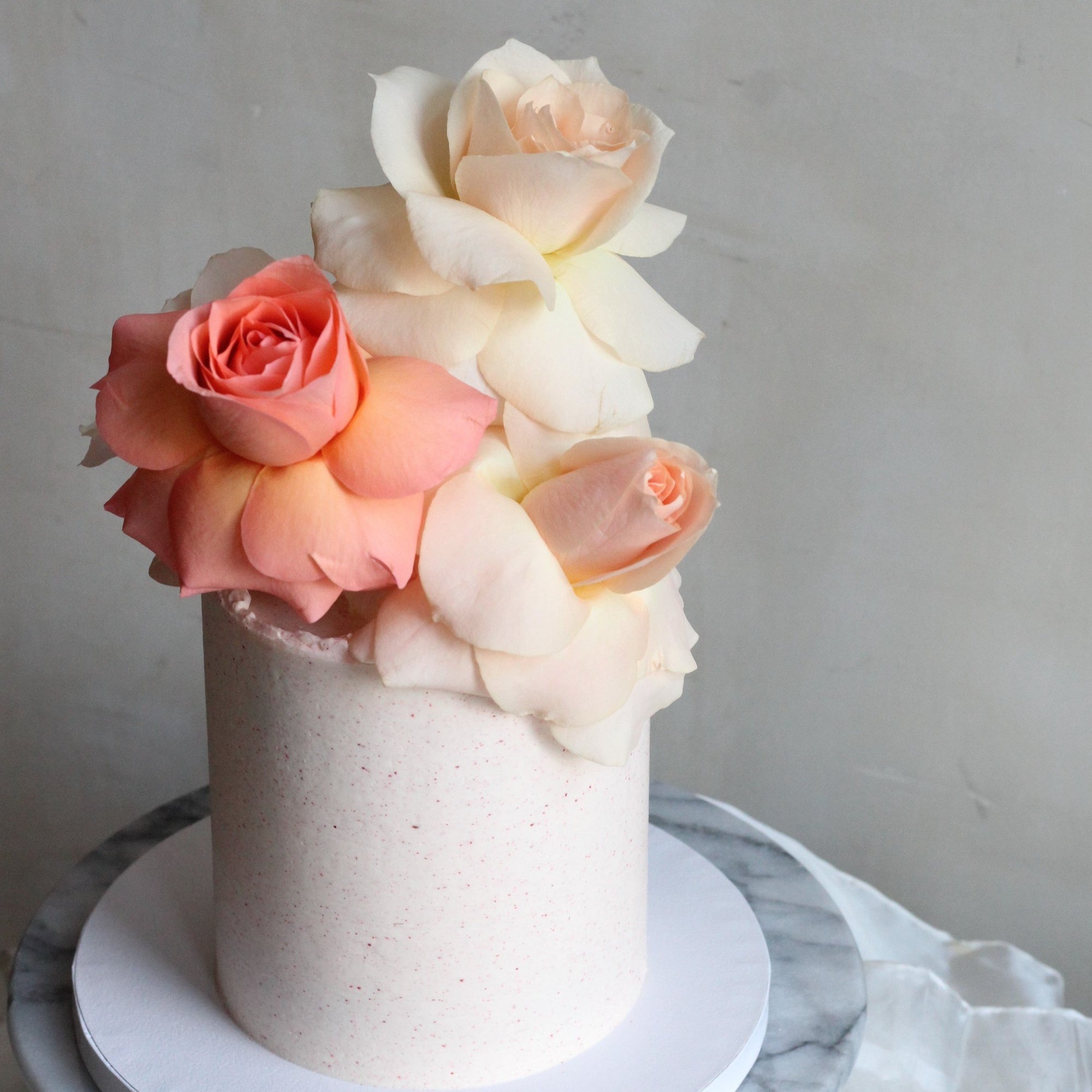 Our seasonal Rosie Cake iced with raspberry cream and topped with fresh roses!