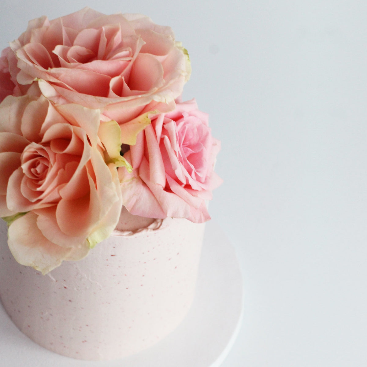 Our seasonal Rosie Cake iced with raspberry cream and topped with fresh roses!