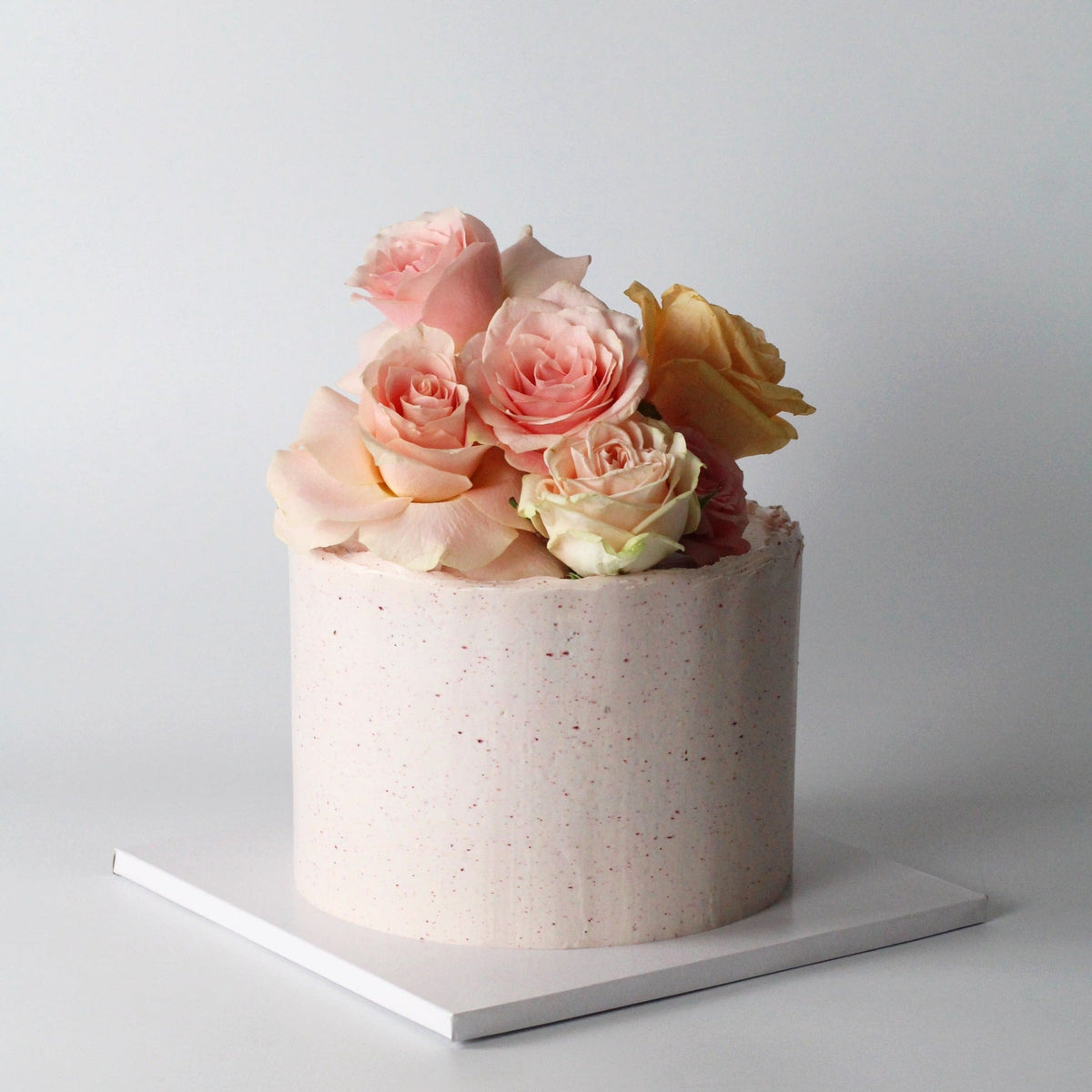 Our seasonal Rosie Cake iced with raspberry cream and topped with fresh roses!